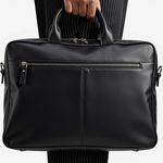 Black leather briefcase held by a person wearing a suit.